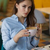 A beautiful woman sitting in a cafe is disturbed by a man approaching her