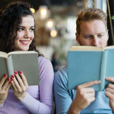 A woman is looking to a man with admiration while reading a book